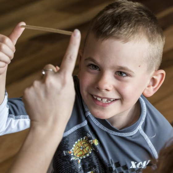 Young male playing a kids yoga game with a chopstick.