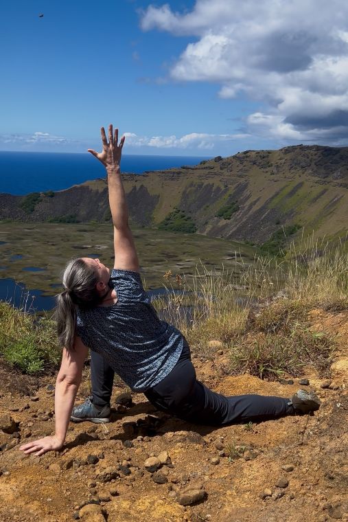 Rapa Nui volcano 2 Donna K Freeman in a twisted lunge pose with volcanic lake behind on Rapa Nui